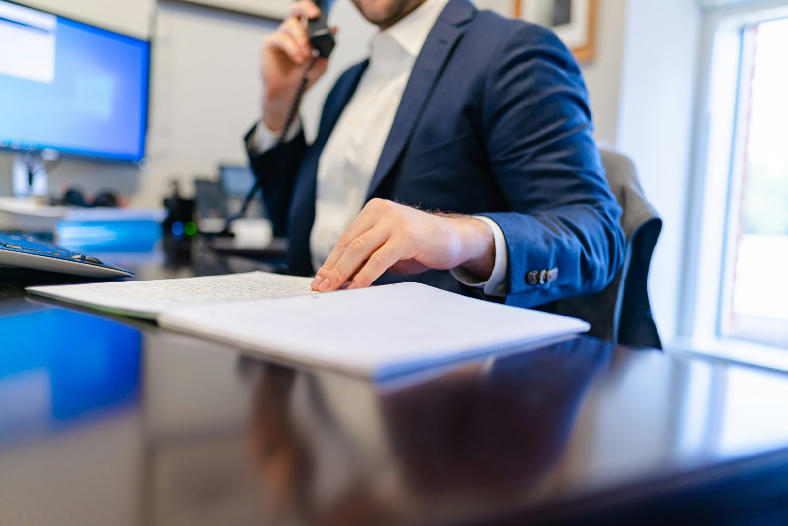 An I-9 compliance attorney on the phone at his desk with an open file in front of him