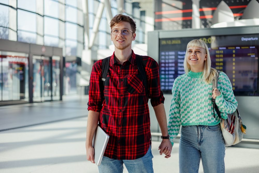 A couple walking through an airport terminal past the departures board on a K-1 fiancé visa