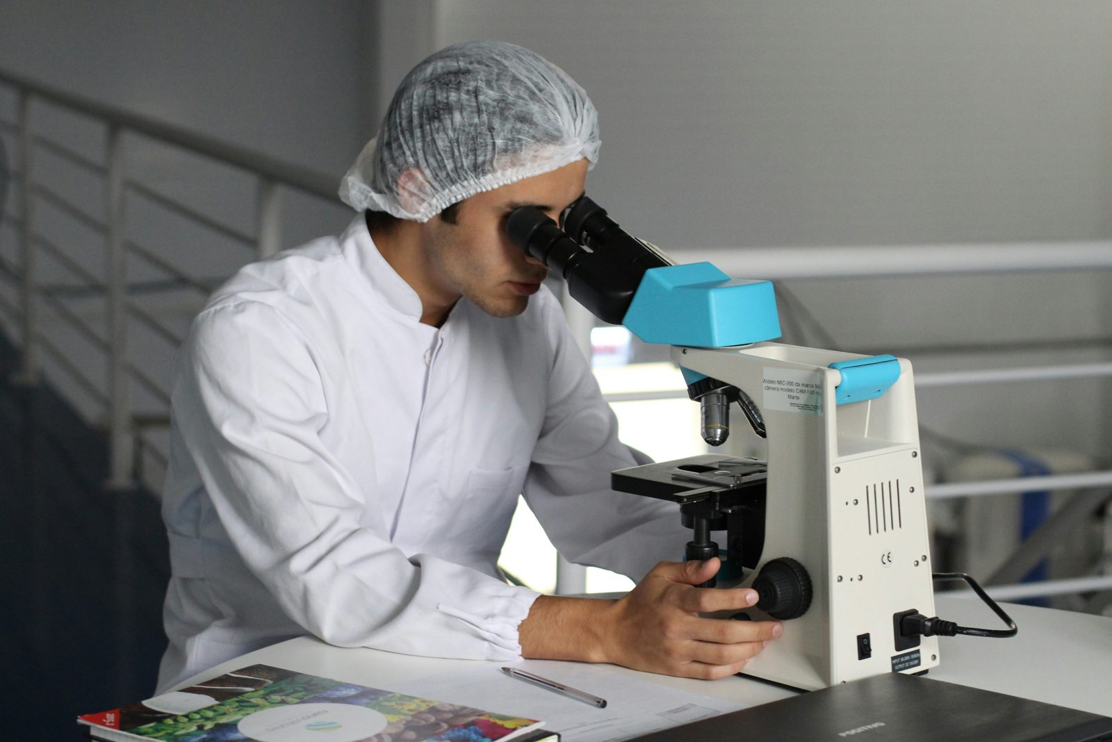 A researcher in a lab coat at a microscope, the kind of record an O-1 visa petition documents