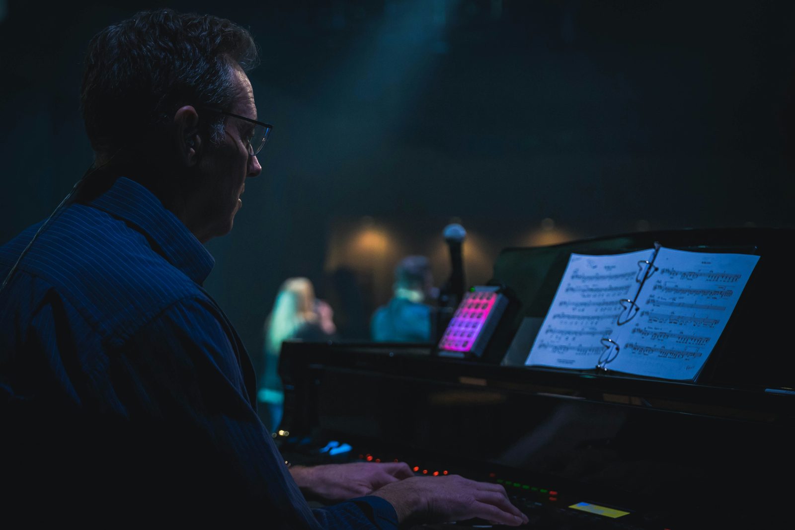 A musician playing a keyboard under stage lights, one of the arts fields an O-1 visa covers